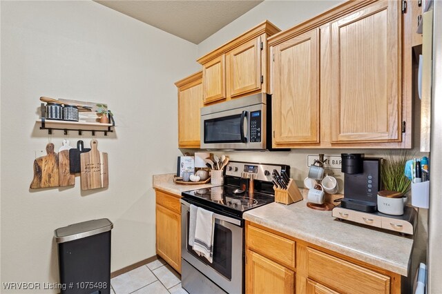 kitchen featuring light brown cabinets, light tile patterned flooring, and appliances with stainless steel finishes