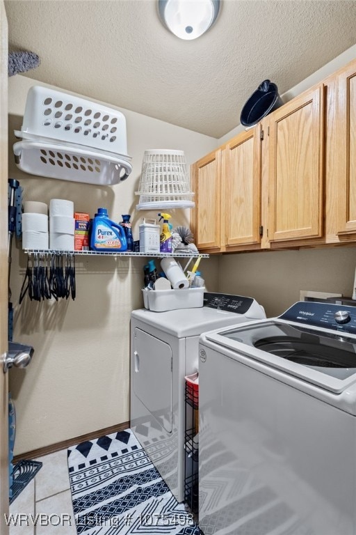 laundry area featuring cabinets, light tile patterned floors, washing machine and dryer, and a textured ceiling