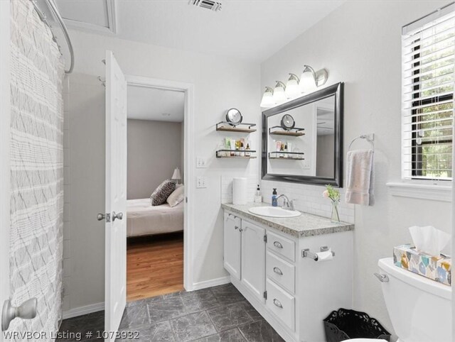 bathroom featuring tasteful backsplash, vanity, and toilet