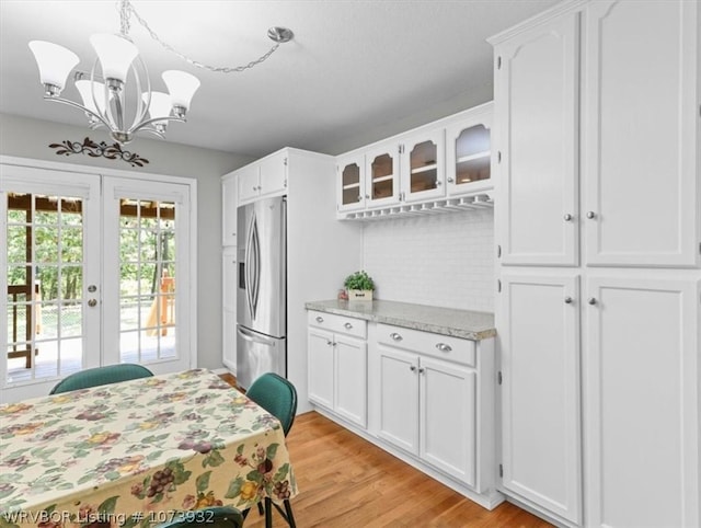 kitchen with white cabinetry, french doors, hanging light fixtures, stainless steel refrigerator with ice dispenser, and light wood-type flooring