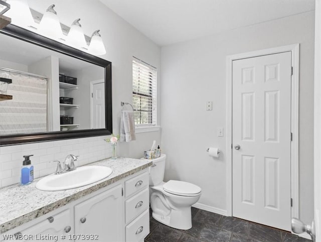 bathroom featuring vanity, toilet, and backsplash