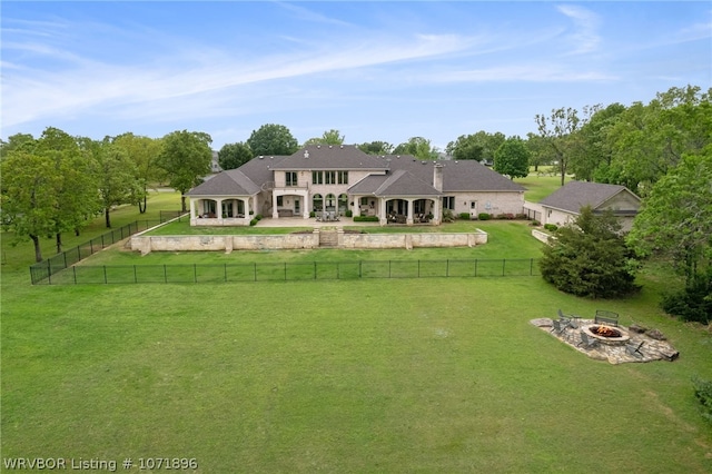 rear view of house with an outdoor fire pit and a lawn