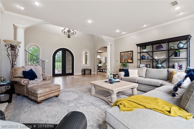 living room featuring decorative columns, french doors, ornamental molding, and a notable chandelier