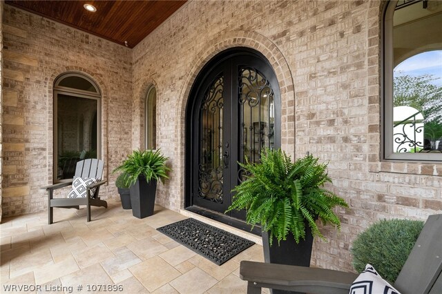 view of exterior entry with covered porch and french doors