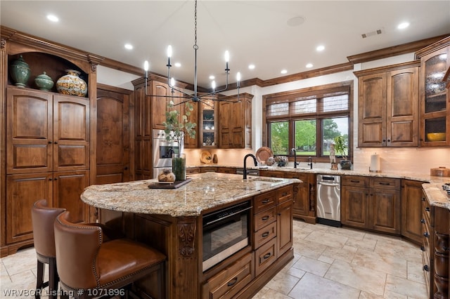 kitchen with a chandelier, light stone counters, hanging light fixtures, and an island with sink