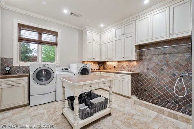 laundry area featuring cabinets, sink, ornamental molding, and independent washer and dryer