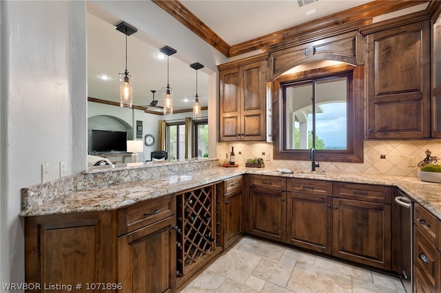 kitchen featuring light stone countertops, hanging light fixtures, crown molding, and sink