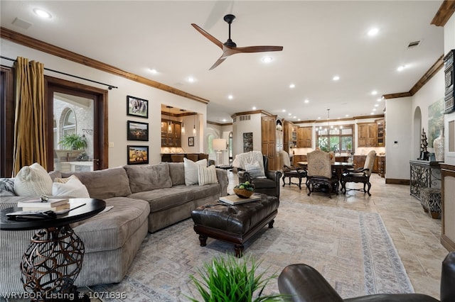 living room with ceiling fan with notable chandelier and crown molding