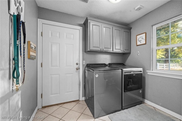 washroom with cabinets, independent washer and dryer, a textured ceiling, and light tile patterned floors