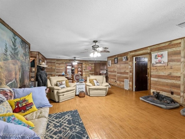 3204 W George, Pocola, OK 74902 - living room featuring a textured ceiling, a ceiling fan, wood finished floors, wooden walls, and a fireplace
