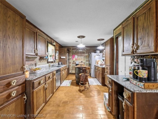 3204 W George, Pocola, OK 74902 - kitchen featuring a textured ceiling, freestanding refrigerator, stainless steel dishwasher, pendant lighting, and light stone counters