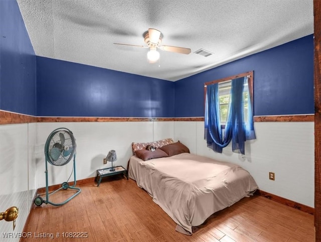 3204 W George, Pocola, OK 74902 - bedroom with wood finished floors, wainscoting, a textured ceiling, and a ceiling fan