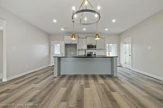 2018 Yellowstone Dr, Barling, AR 72903 - kitchen featuring stainless steel appliances, a center island with sink, baseboards, wood finished floors, and recessed lighting