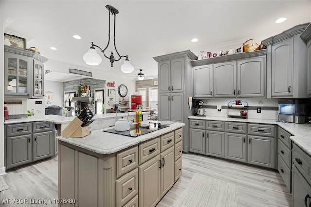 kitchen featuring pendant lighting, black electric cooktop, a kitchen island, and gray cabinetry