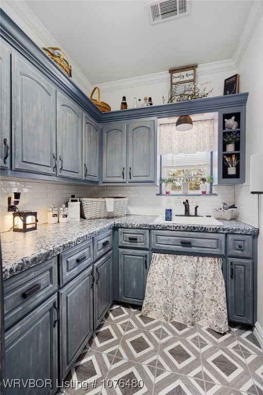 kitchen with decorative backsplash, light stone counters, sink, and ornamental molding