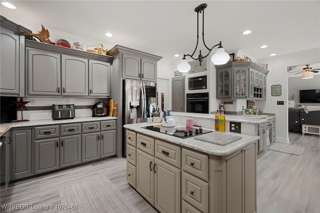 kitchen featuring ceiling fan, crown molding, black appliances, decorative light fixtures, and a center island