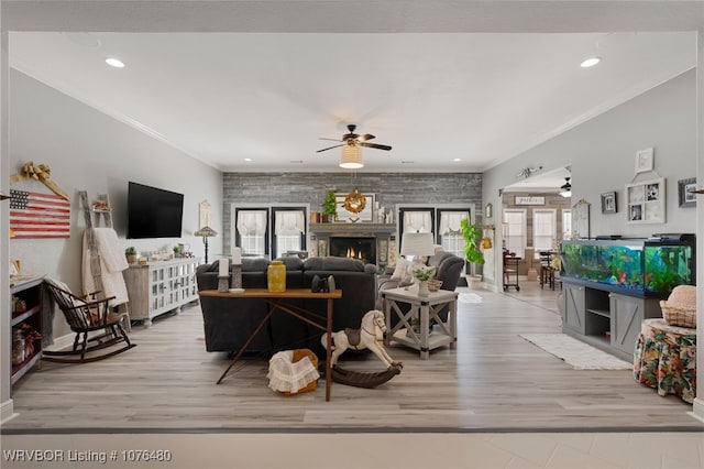 living room featuring ceiling fan, light wood-type flooring, and ornamental molding