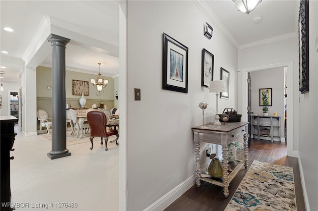 corridor featuring an inviting chandelier, wood-type flooring, ornamental molding, and decorative columns