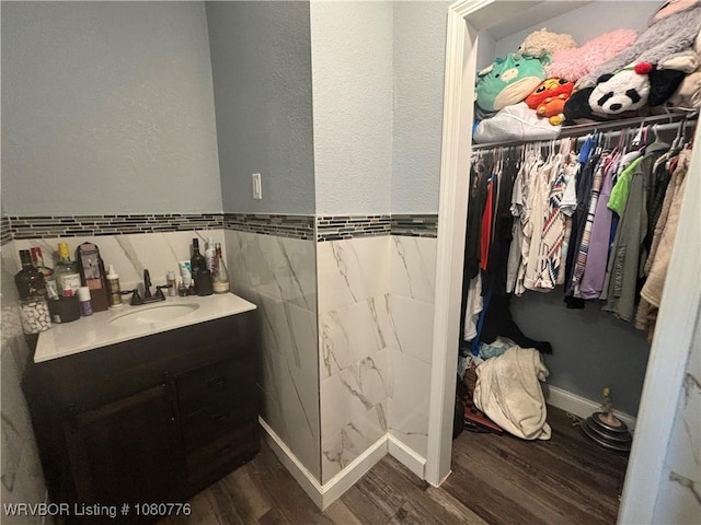 420 Wheeler Ave, Sallisaw, OK 74955 - bathroom featuring tile walls, wainscoting, vanity, wood finished floors, and a spacious closet