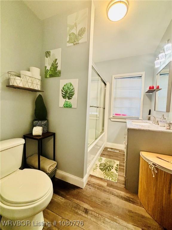 420 Wheeler Ave, Sallisaw, OK 74955 - bathroom featuring toilet, baseboards, vanity, and hardwood / wood-style flooring