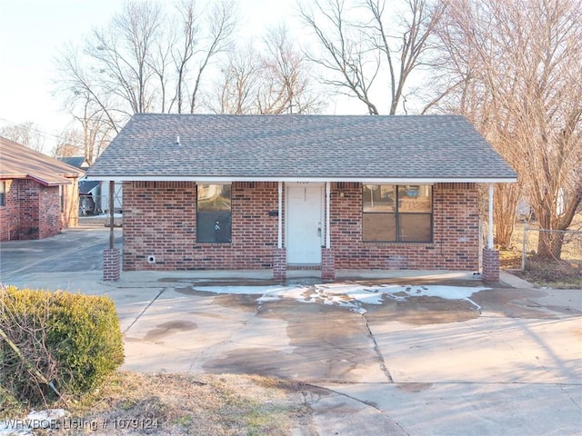 ranch-style house featuring roof with shingles and brick siding