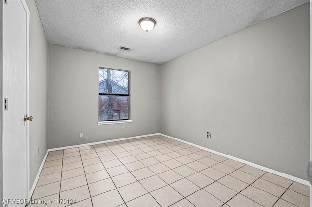 empty room with a textured ceiling, visible vents, and baseboards