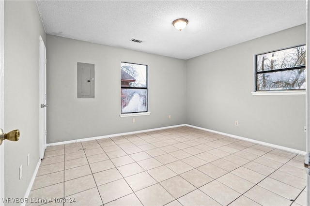 unfurnished room featuring visible vents, a textured ceiling, electric panel, and baseboards