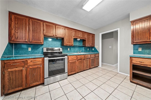 kitchen with electric stove, brown cabinetry, dark countertops, and a sink