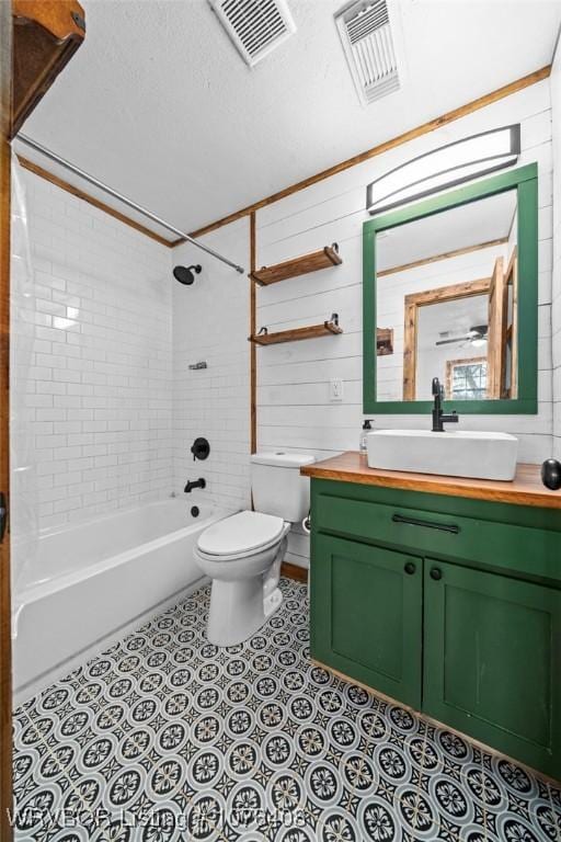 full bathroom with tile patterned floors, toilet, wooden walls, vanity, and tiled shower / bath