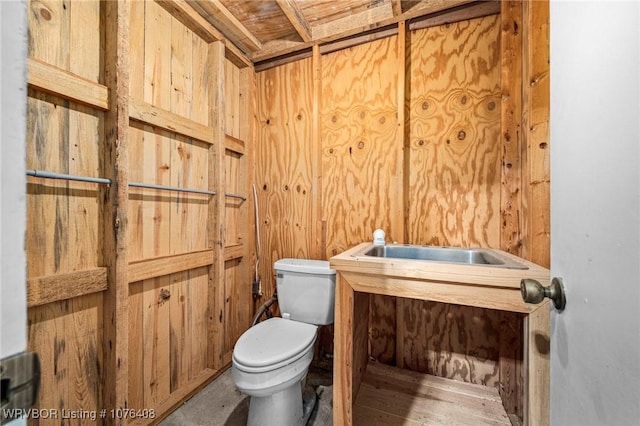 bathroom featuring toilet and wooden walls