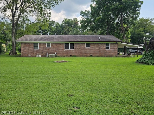 back of property featuring a carport, cooling unit, and a lawn