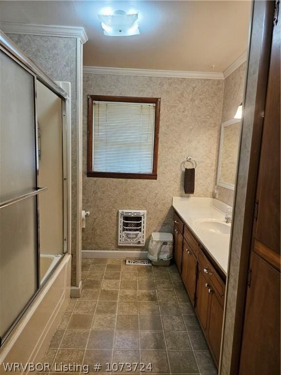 bathroom featuring heating unit, vanity, combined bath / shower with glass door, and ornamental molding