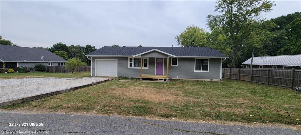 view of front facade featuring a front lawn, gravel driveway, a garage, and fence