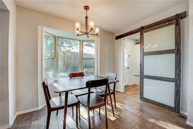 dining area featuring a chandelier, wood finished floors, and baseboards