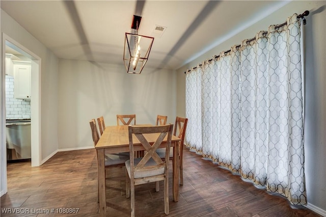 dining room featuring dark wood finished floors, a chandelier, and baseboards