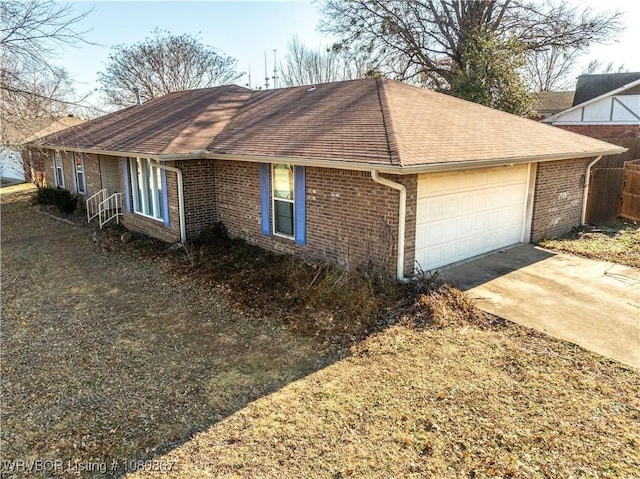 view of home's exterior featuring brick siding, a shingled roof, an attached garage, and driveway
