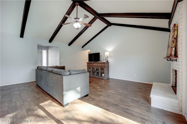 unfurnished living room featuring ceiling fan, wood finished floors, beam ceiling, a fireplace, and baseboards