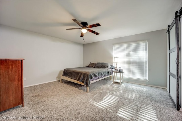 carpeted bedroom featuring a barn door, baseboards, and ceiling fan
