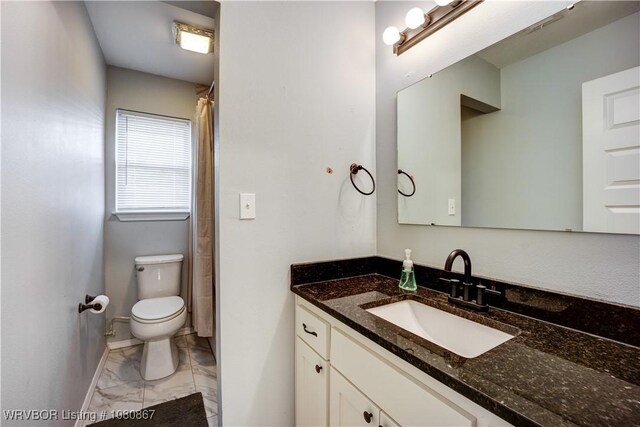 bathroom with marble finish flooring, toilet, vanity, and baseboards