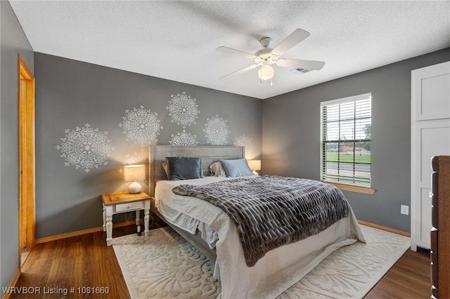103 Bowlin Dr, Poteau, OK 74953 - bedroom with wood finished floors, ceiling fan, and a textured ceiling