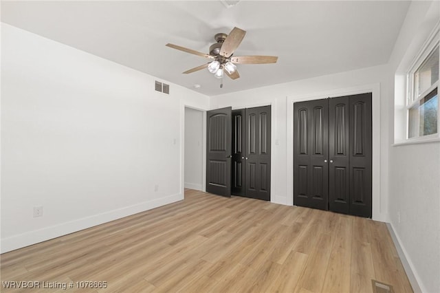 unfurnished bedroom with two closets, ceiling fan, and light hardwood / wood-style flooring