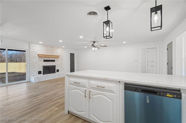 kitchen with white cabinetry, decorative light fixtures, light hardwood / wood-style flooring, stainless steel dishwasher, and a large fireplace