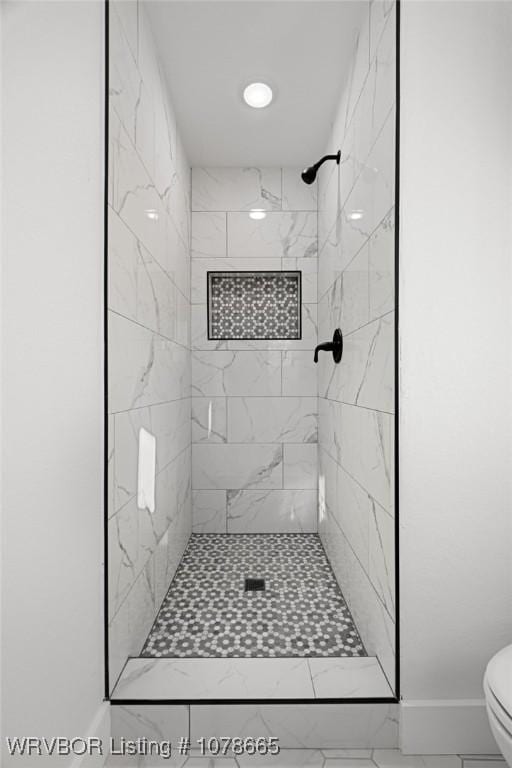 bathroom featuring a tile shower and toilet