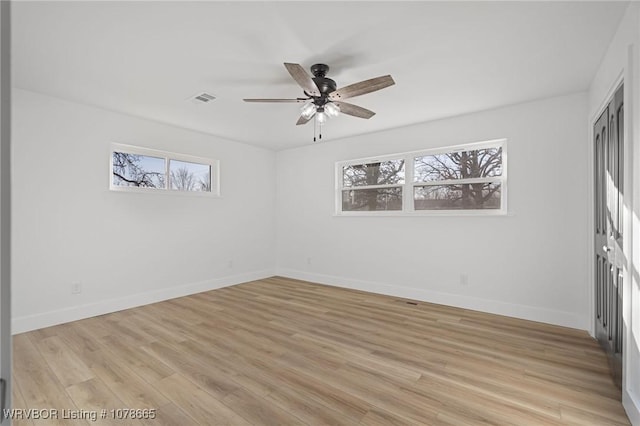 empty room with ceiling fan, a healthy amount of sunlight, and light hardwood / wood-style floors