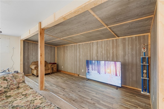 unfurnished bedroom with wood walls, wood finished floors, and electric panel