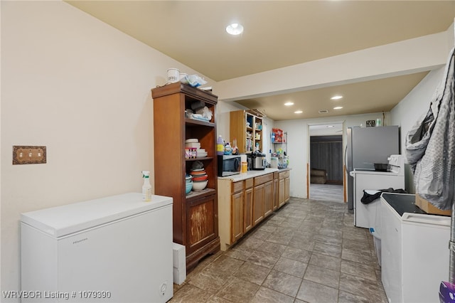 kitchen with recessed lighting, fridge, brown cabinets, open shelves, and stainless steel microwave