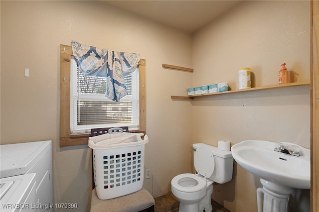 bathroom with toilet, washing machine and dryer, and a sink