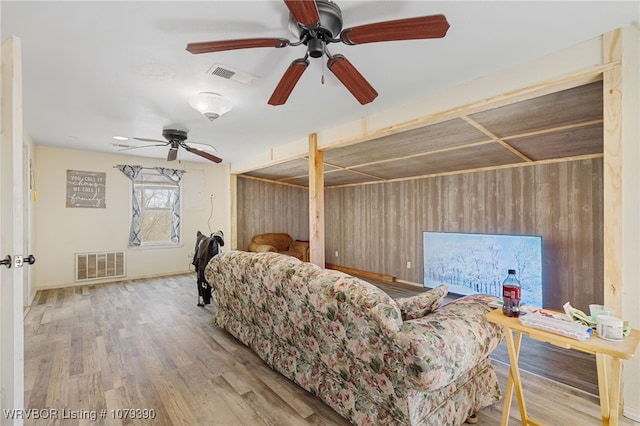 living room featuring wood walls, visible vents, and wood finished floors