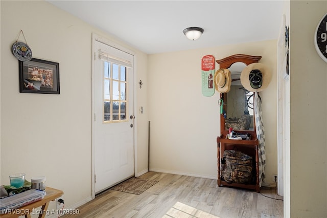 doorway to outside featuring baseboards and wood finished floors