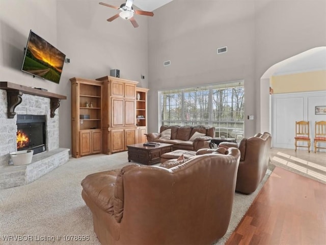 living room with a stone fireplace and ceiling fan